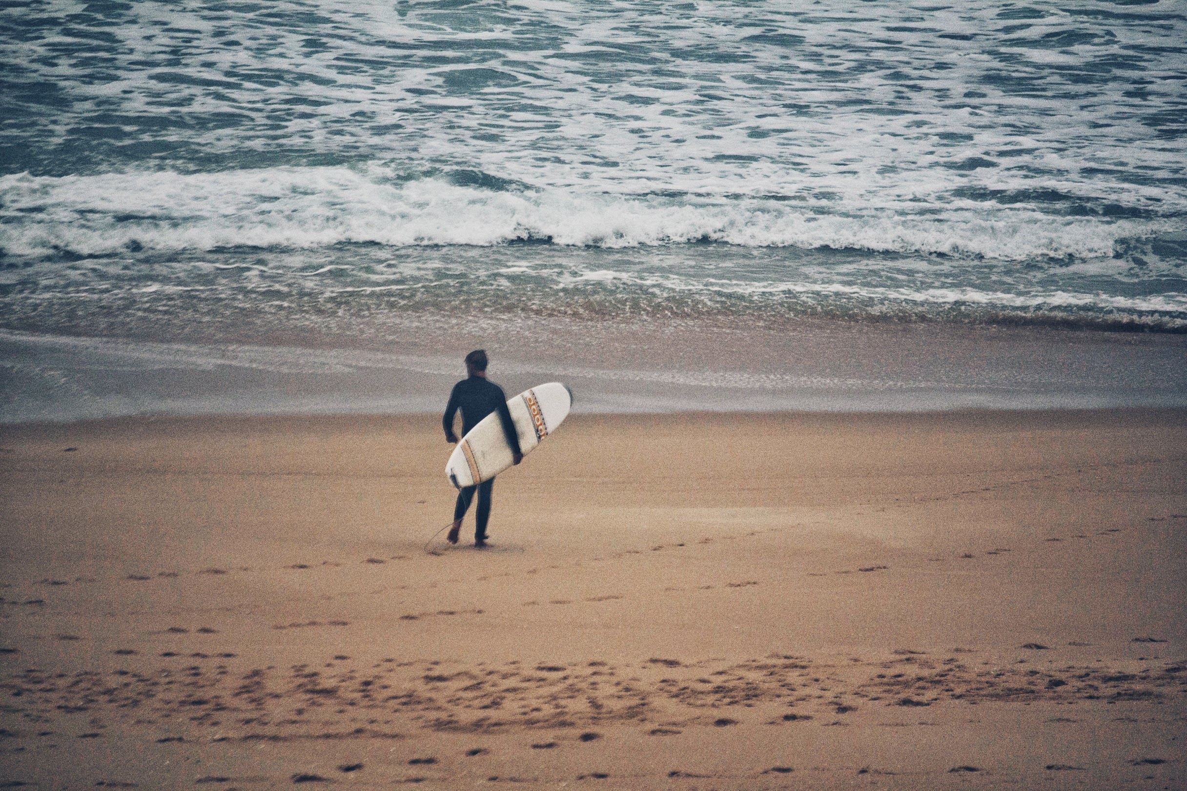 A surfer approaches the water at Afife beach, Northern Portugal.